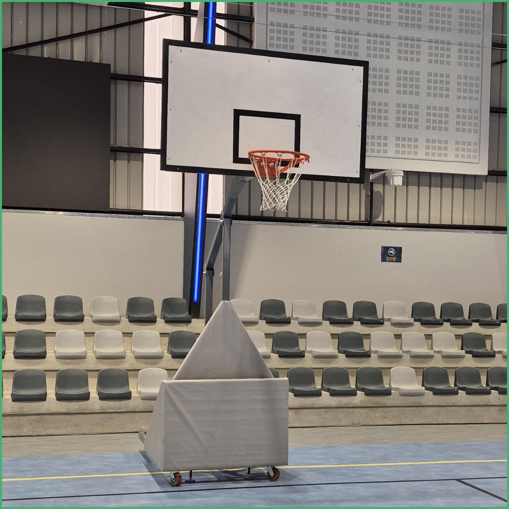 Synsport sports equipment - Basketball Folding Club 3 | Synsport Portable basketball hoop with white backboard and orange rim on a gym floor; padded wheeled base and empty gray seating in the background.