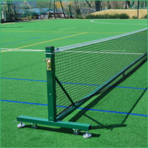 Portable tennis net on an outdoor artificial turf court with wheels and a secure base frame.