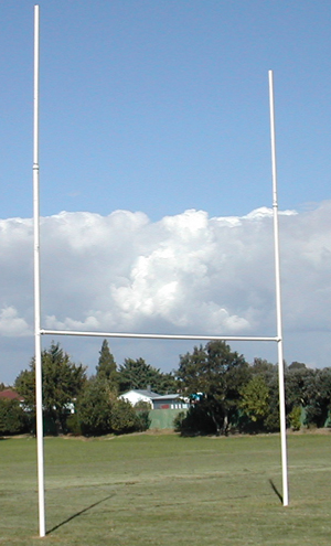 GT Rugby Posts 10m Standard Mild Steel 3 | Synsport Rugby goalposts standing on a grassy field beneath a blue, partly cloudy sky.