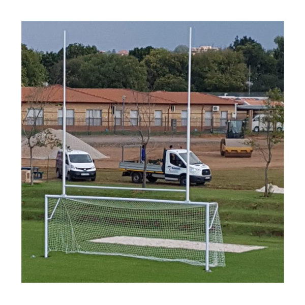 GT soccer rugby combination posts 1 | Synsport Soccer goal on a grassy field with a white frame and net; construction vehicles and a low building are visible in the background.