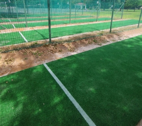Syn Club 10mm | Synsport Artificial turf field with a white boundary line and a green chain-link fence in the background.