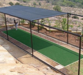 Syn Fibre Pro 7MM | Synsport Outdoor mini-golf putting green under a metal canopy, with two players in the distance.