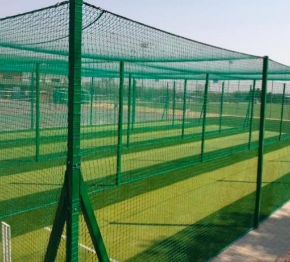 Syn OVAL 11mm | Synsport Green metal-framed netted enclosure for a sports practice area outdoors, with posts and casting shadows on the ground.