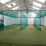 Synthetic Cricket Facilities BISHOPS DIOCESAN COLLEGE | Synsport Indoor cricket practice nets with green netting and artificial turf bays for batting drills in a large training hall.