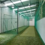Synthetic Cricket Facilities Montague Arena Cricket Academy | Synsport Indoor cricket nets: a long narrow practice lane with netting walls and a green turf floor at an indoor facility