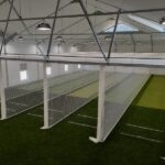 Synthetic Cricket Facilities Paul Roos | Synsport Indoor sports facility with four netted batting bays and artificial turf in a warehouse-style gym.