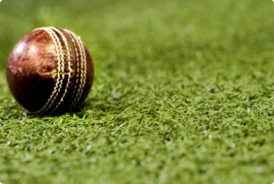 Synthetic Cricket Facilities - img1 | Synsport Cricket ball resting on a green grass field in close-up view.