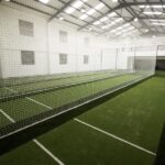 Synthetic Cricket Facilities no name 1 | Synsport Indoor sports hall with long cricket practice nets and artificial turf inside a bright white facility.