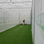 Synthetic Cricket Facilities no name 3 | Synsport Cricketer in practice nets preparing to bat inside a long indoor cricket cage with green artificial turf and netting on all sides,"
