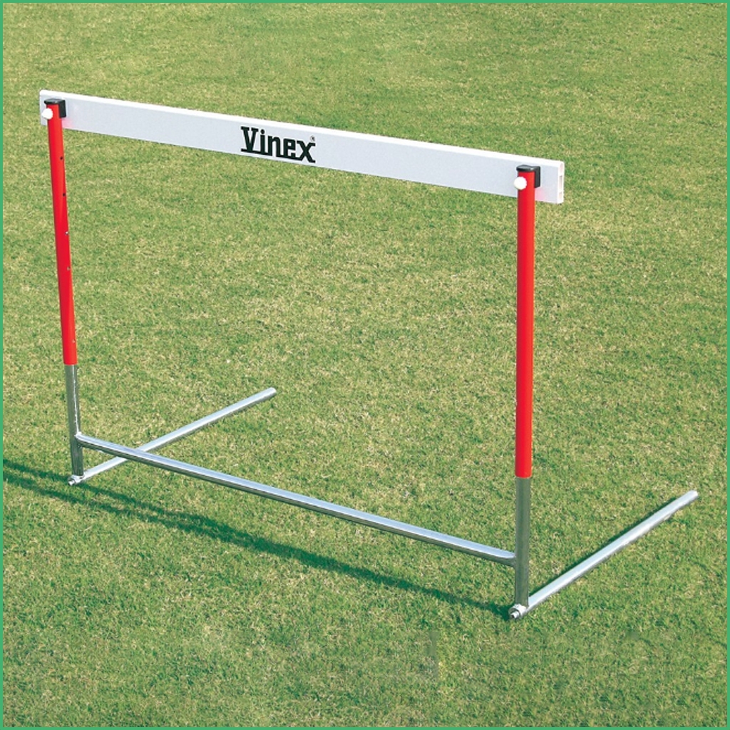 Synsport sports equipment - basic hurdle 1 | Synsport Athletic hurdle on a grassy field with red vertical posts and a white crossbar labeled 'Vinex' for jump training